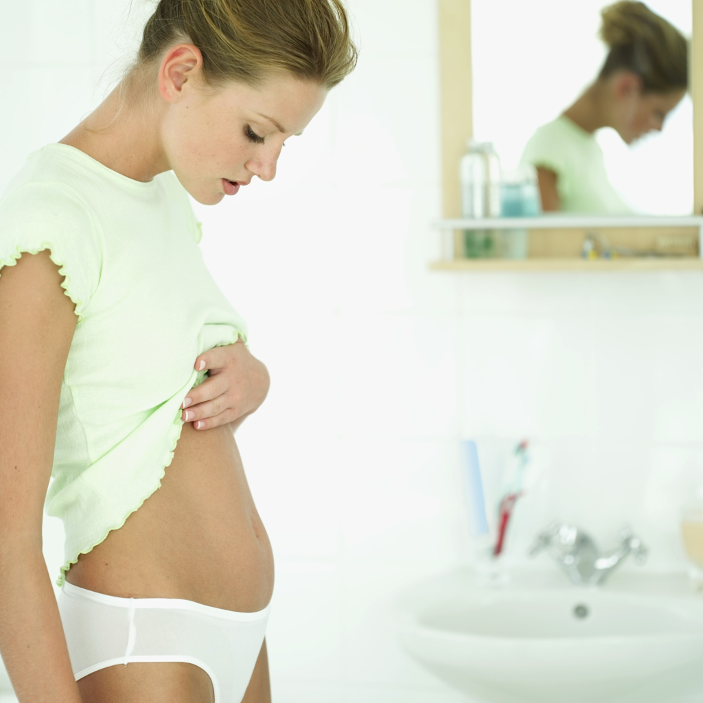 side view of a woman looking down at her exposed stomach